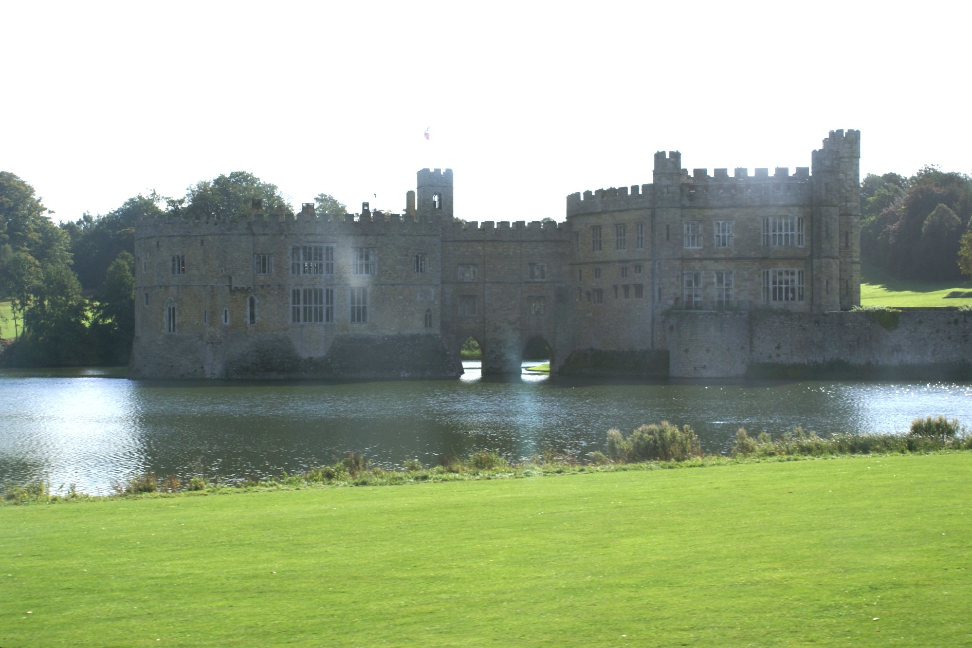 Stone castle on an island in a lake with arched bridges connecting it to the shore