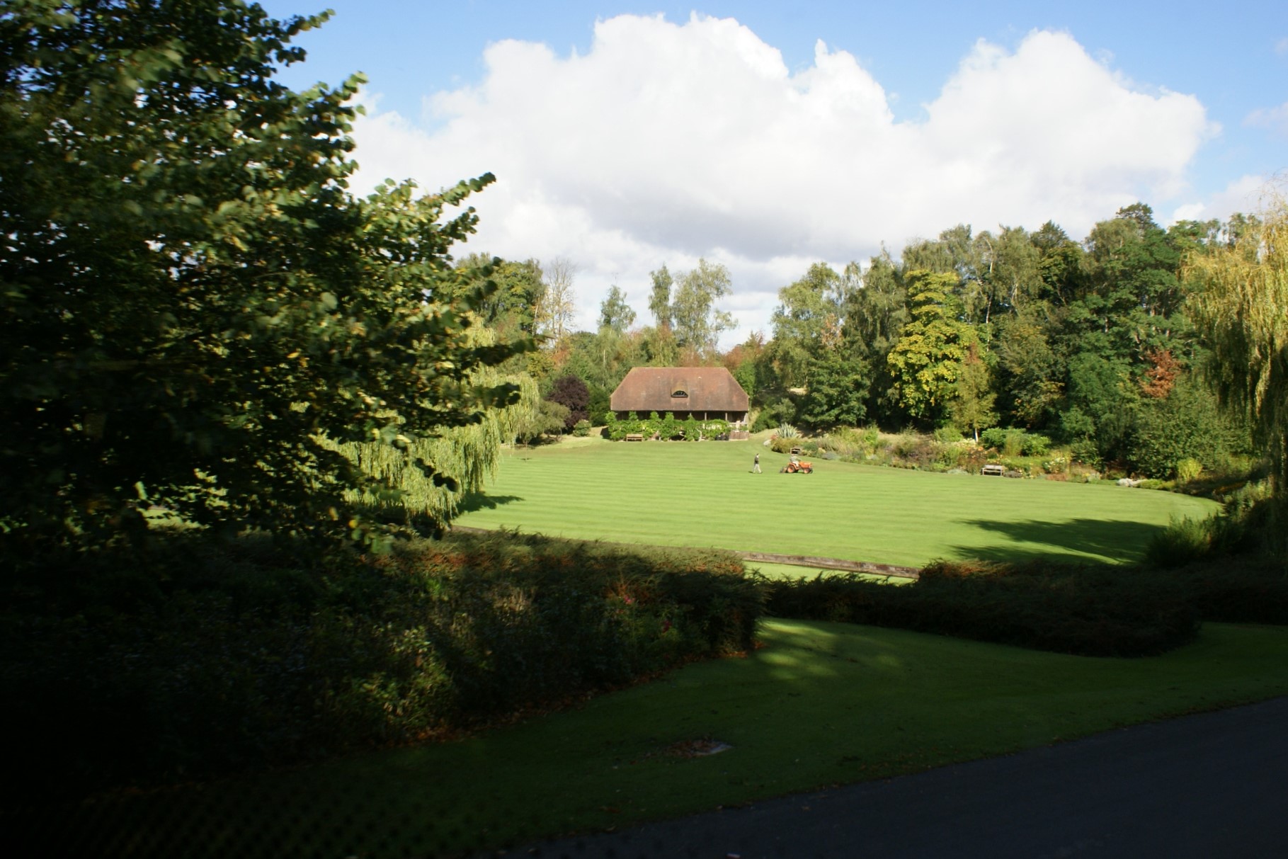 Green lawn surrounded by old trees with a historic barn on the far end