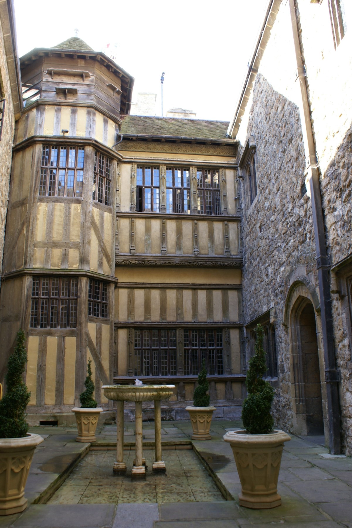 A courtyard shows stone walls on one side with Tudor style wood and stucco on another