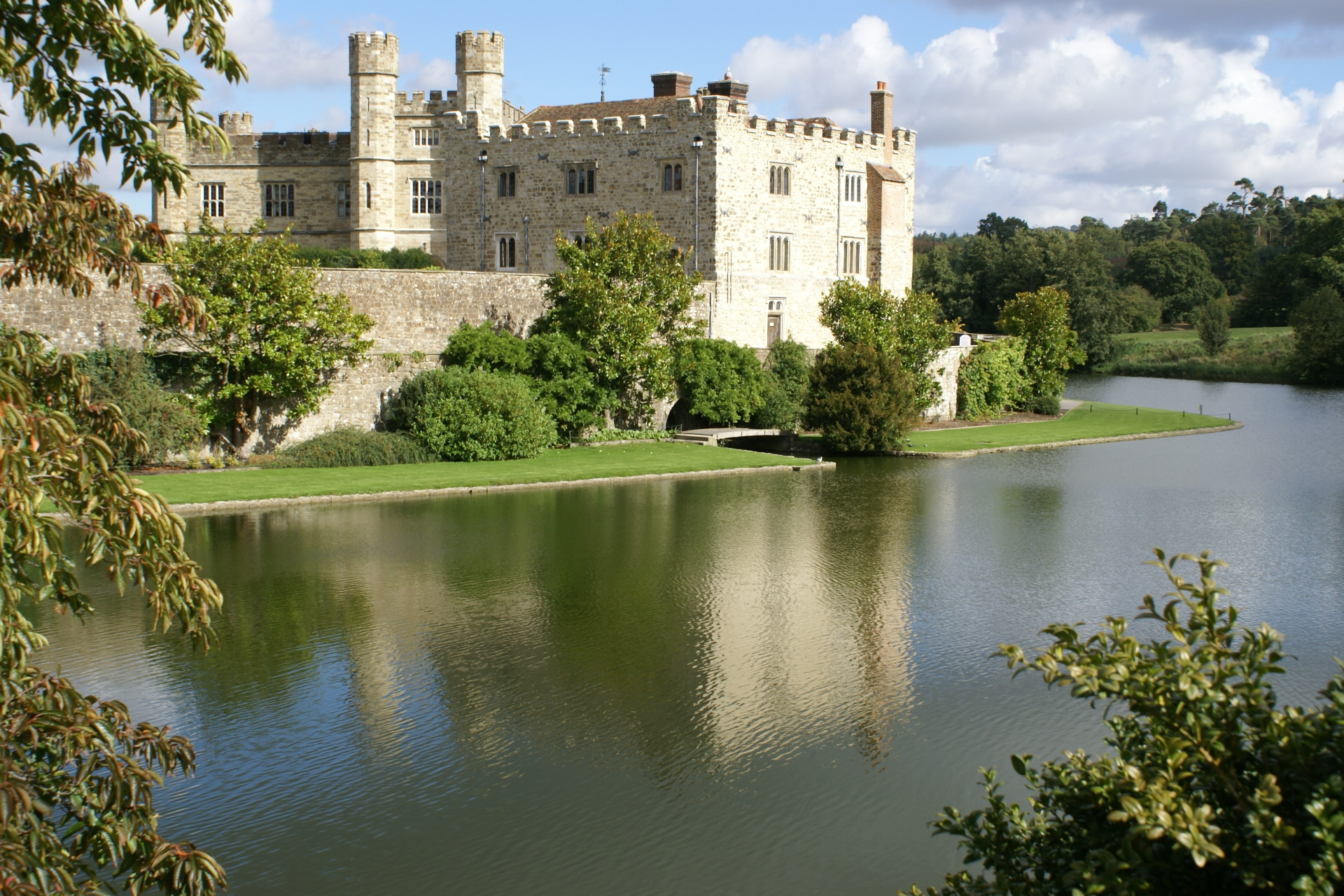 Castle and main entry bridge reflected in water around the base
