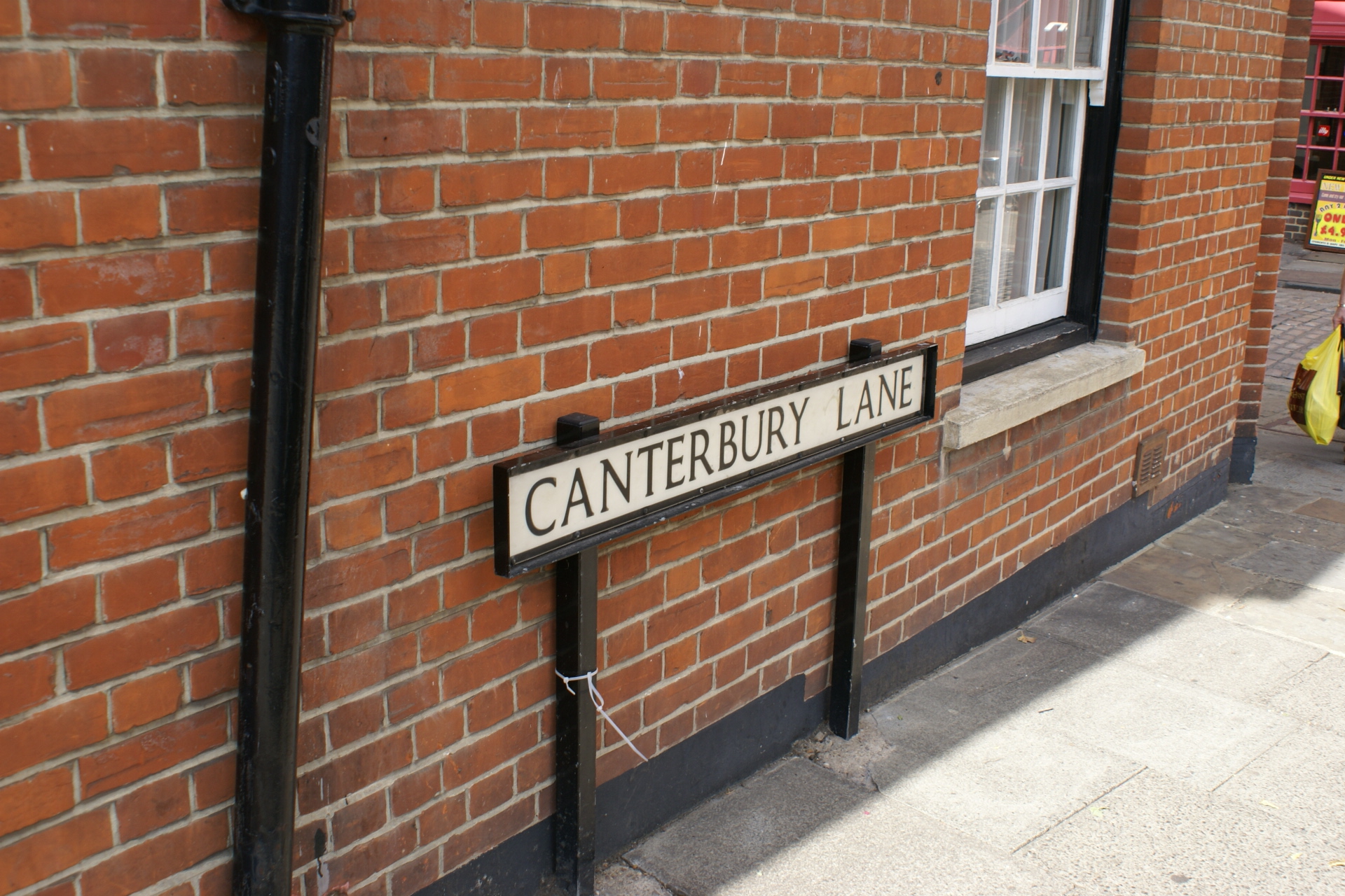 White sign reading 'Canterbury Road' in front of red brick wall