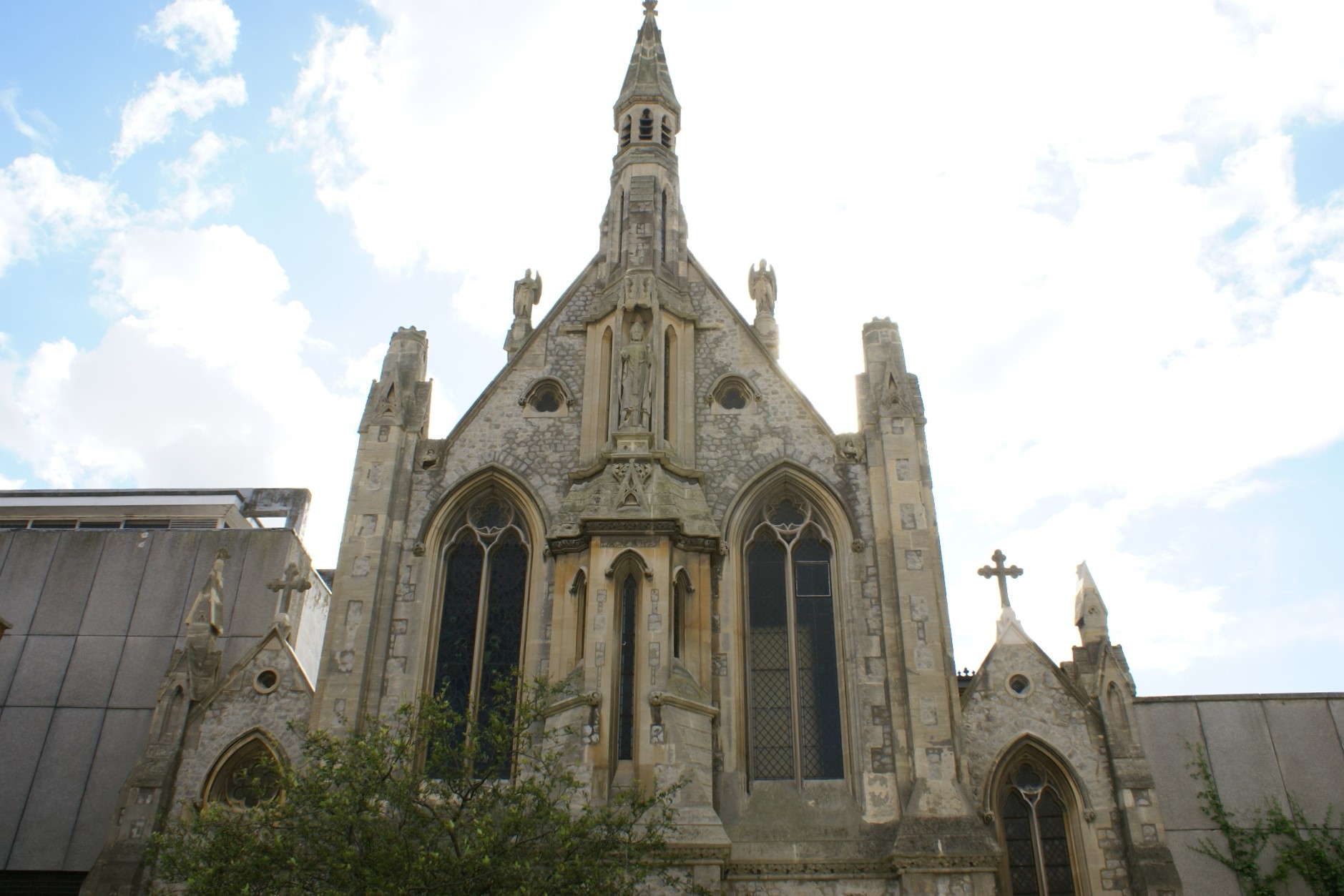 White stone church front with gothic detailing and windows