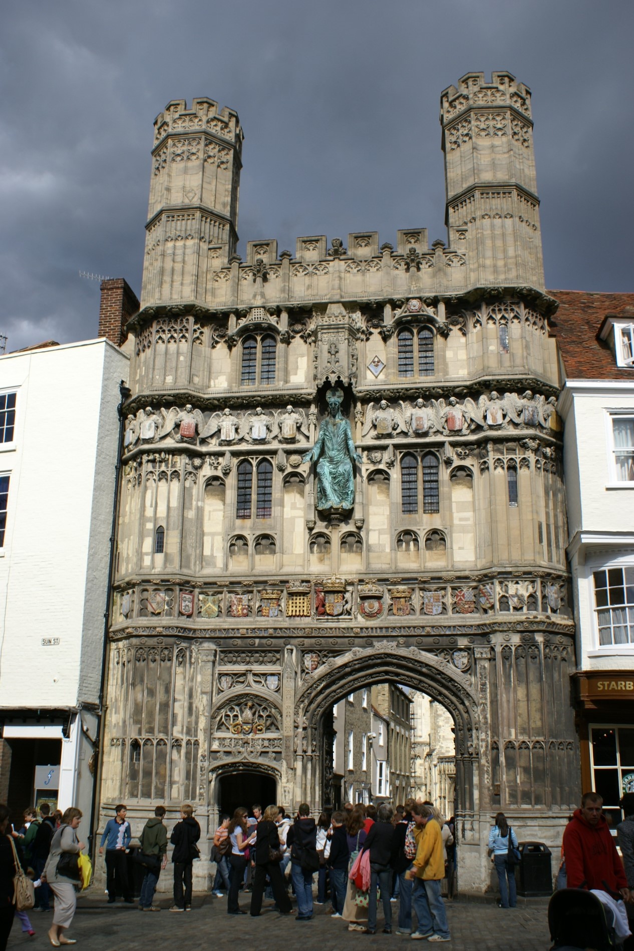 A four-story stone façade with intricate carvings and a 10-foot copper statue pinched between shops