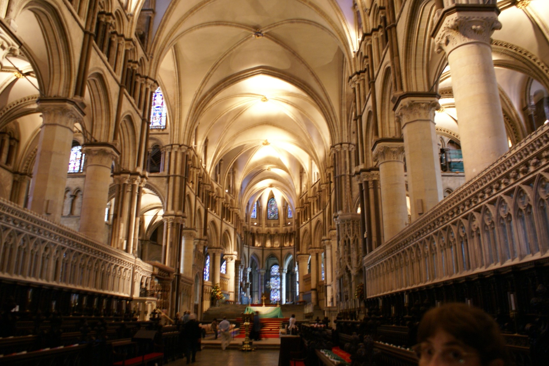 White columns and arches support vaulted ceiling over rows of carved wood benches for influential members of the church