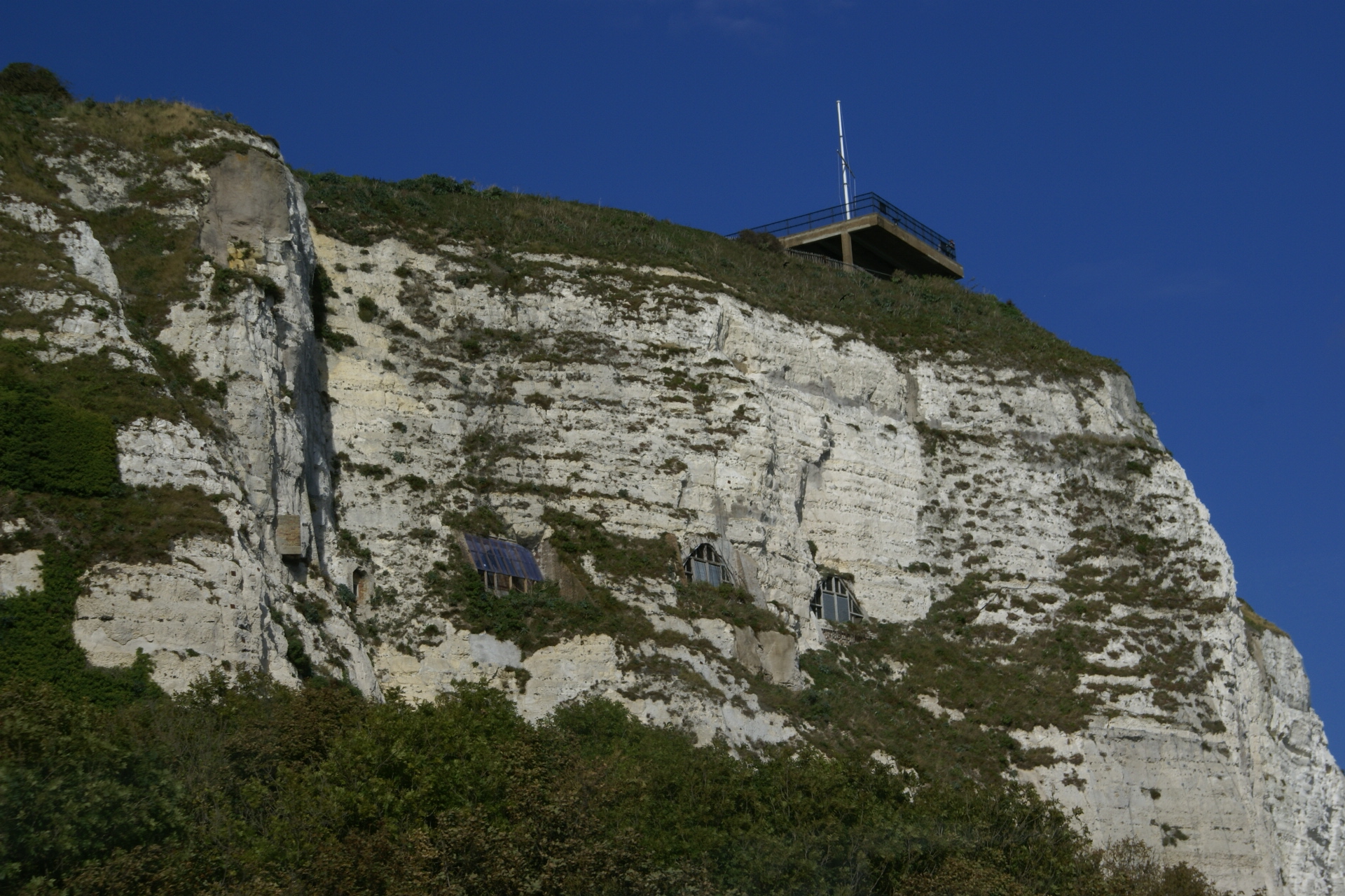 Glass partitions protect the entrances to caves in a white stone wall