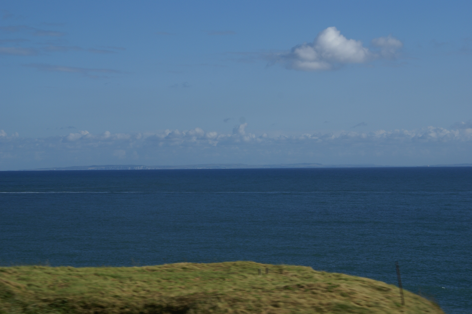 Low hills visible in the haze of the distance across dark blue water