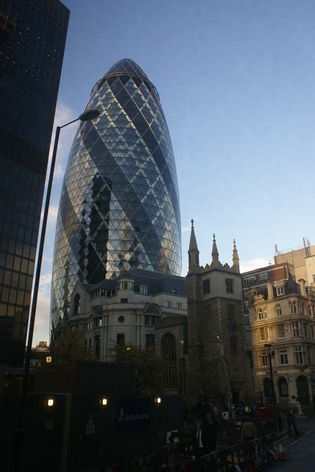 Tower of green and gray glass shaped like a bullet extends toward the sky