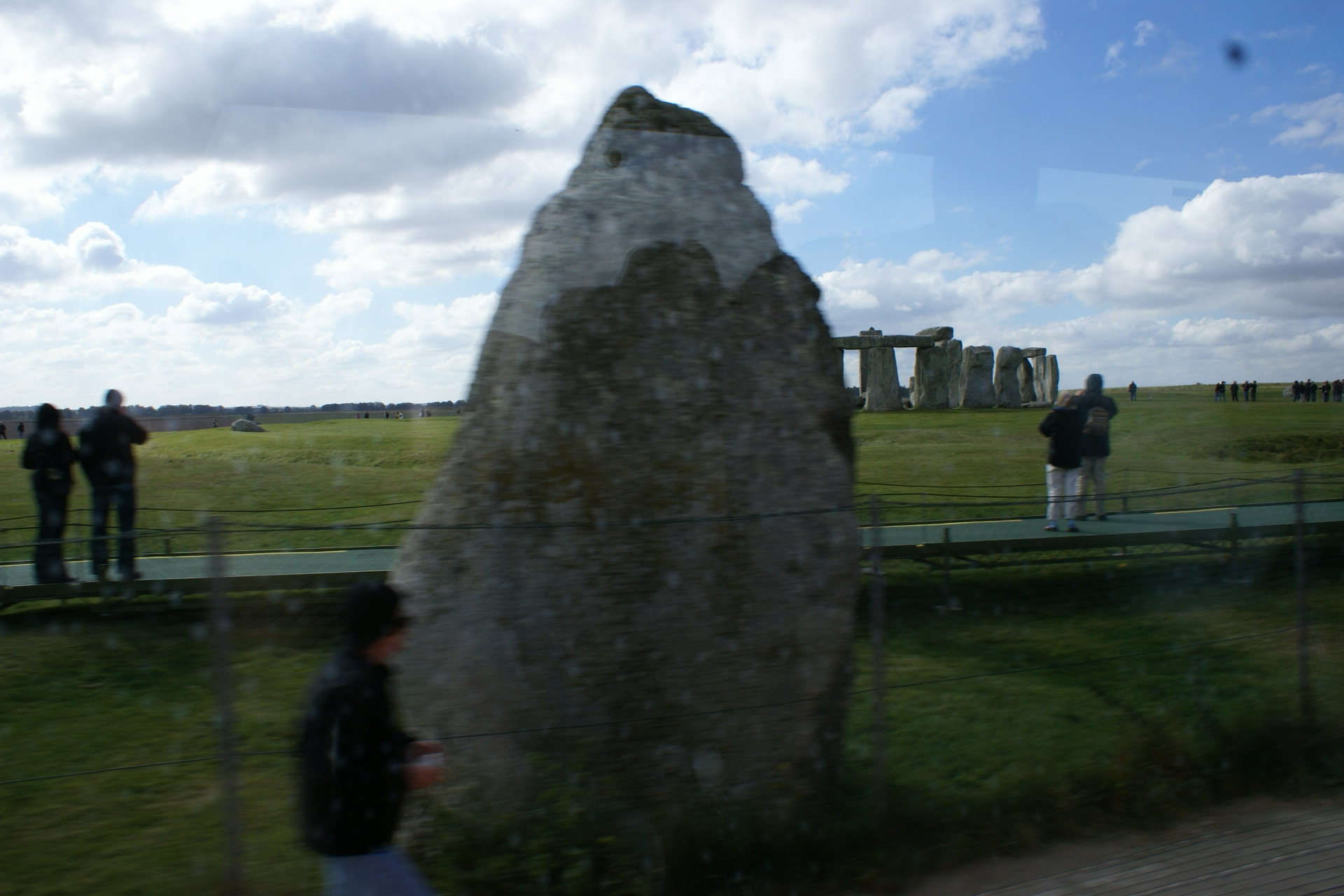 A large rough-hewn grey stone sticks up from the ground near a walking path