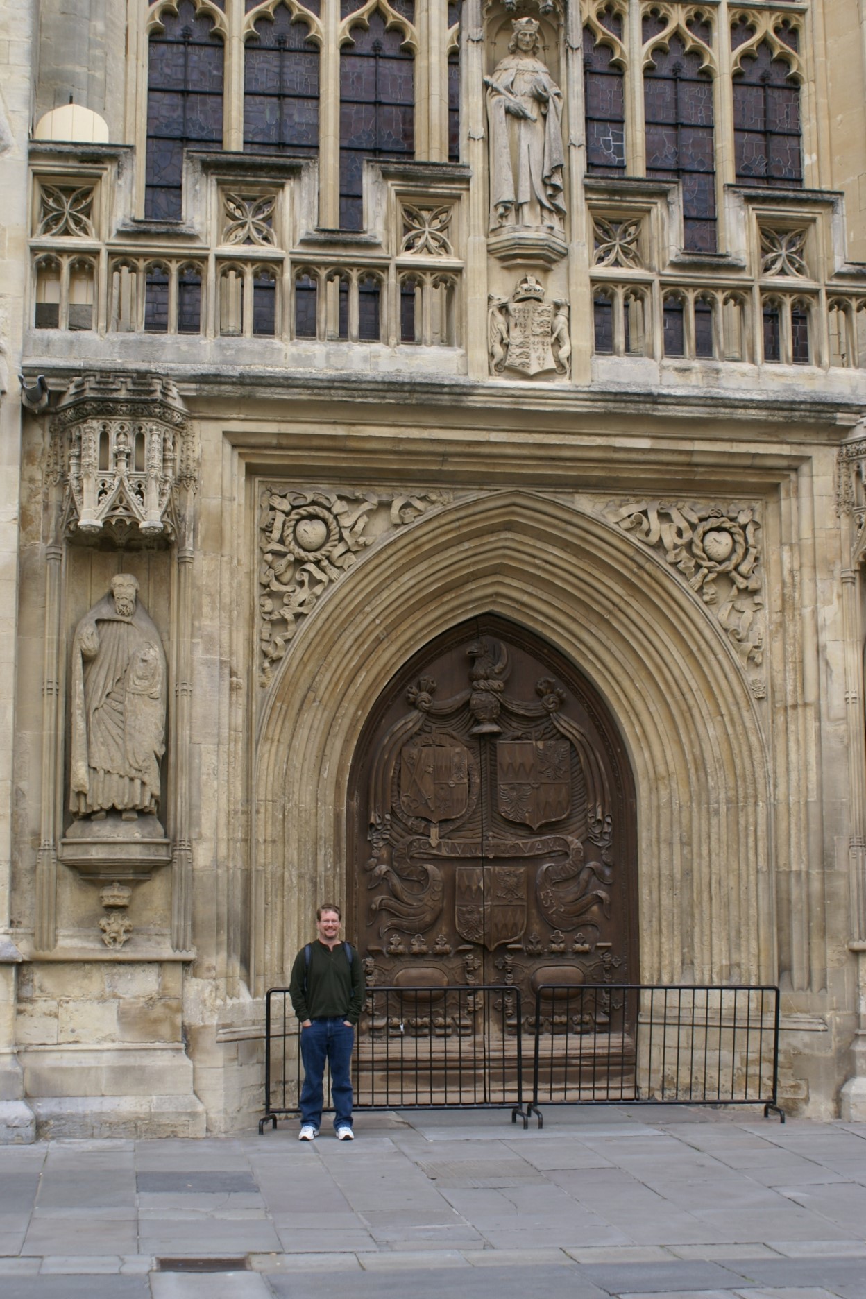 James stands by large arched wood doors set in a richly carved stone wall
