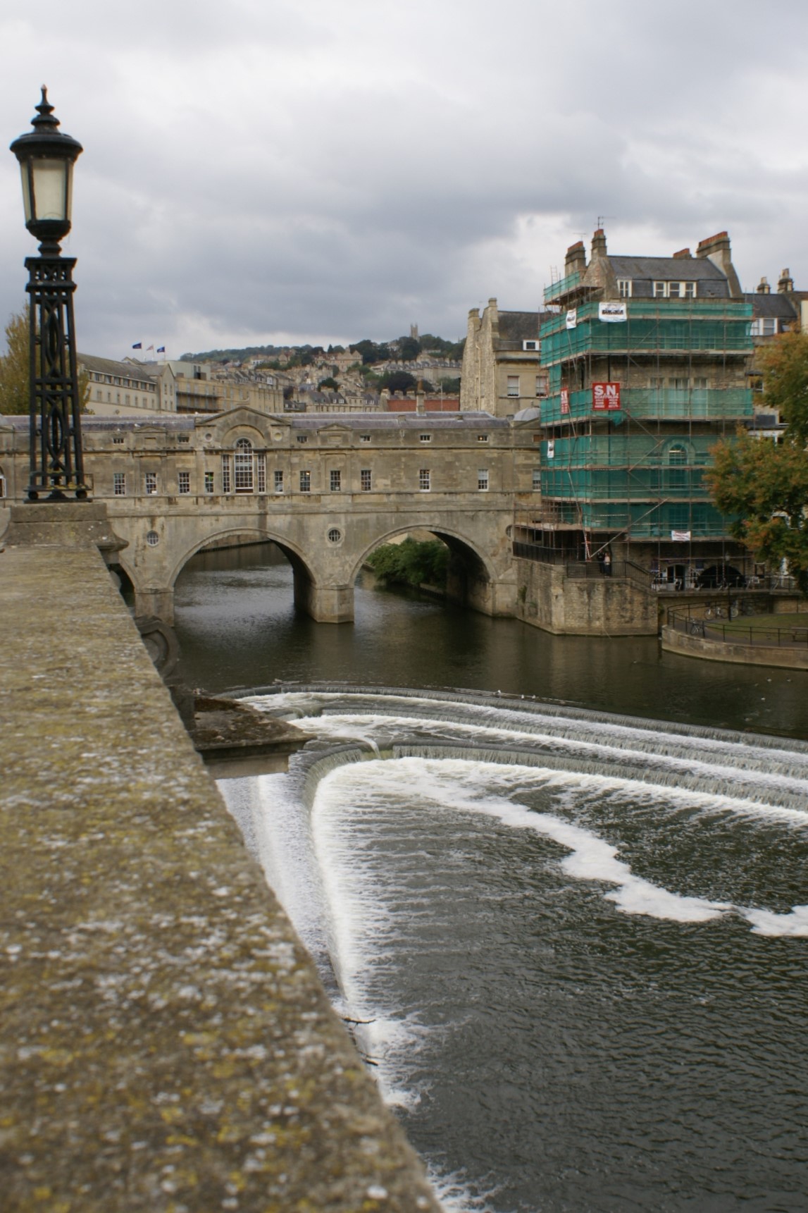 A river flows under a bridge with stone arches and sidewalls