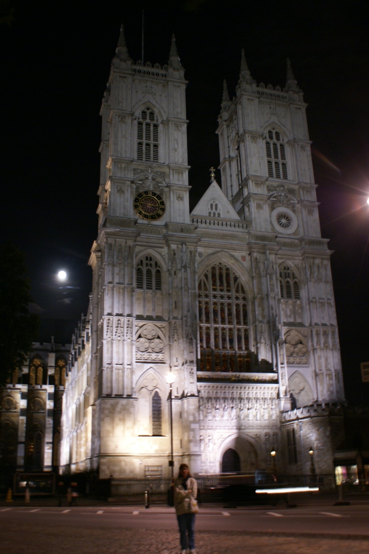 A white church wall with two towers lit from the ground a night