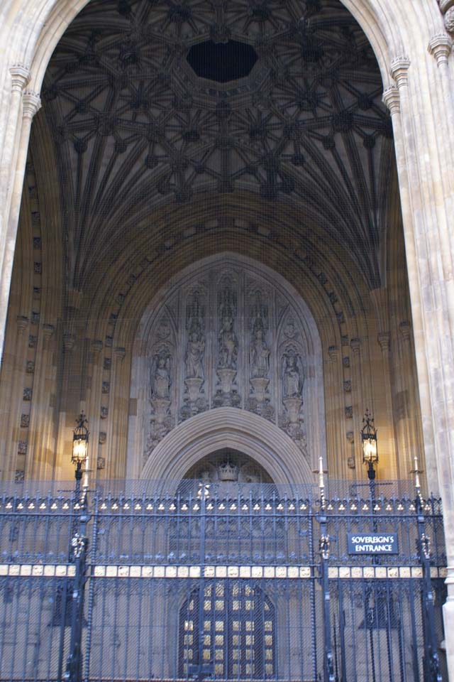 Intricate stone ceiling in large arched space behind heavy wrought iron fence