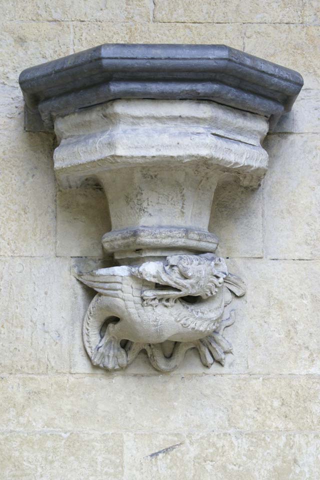 Closeup shot of stone wall sconce with carved dragon at base of support