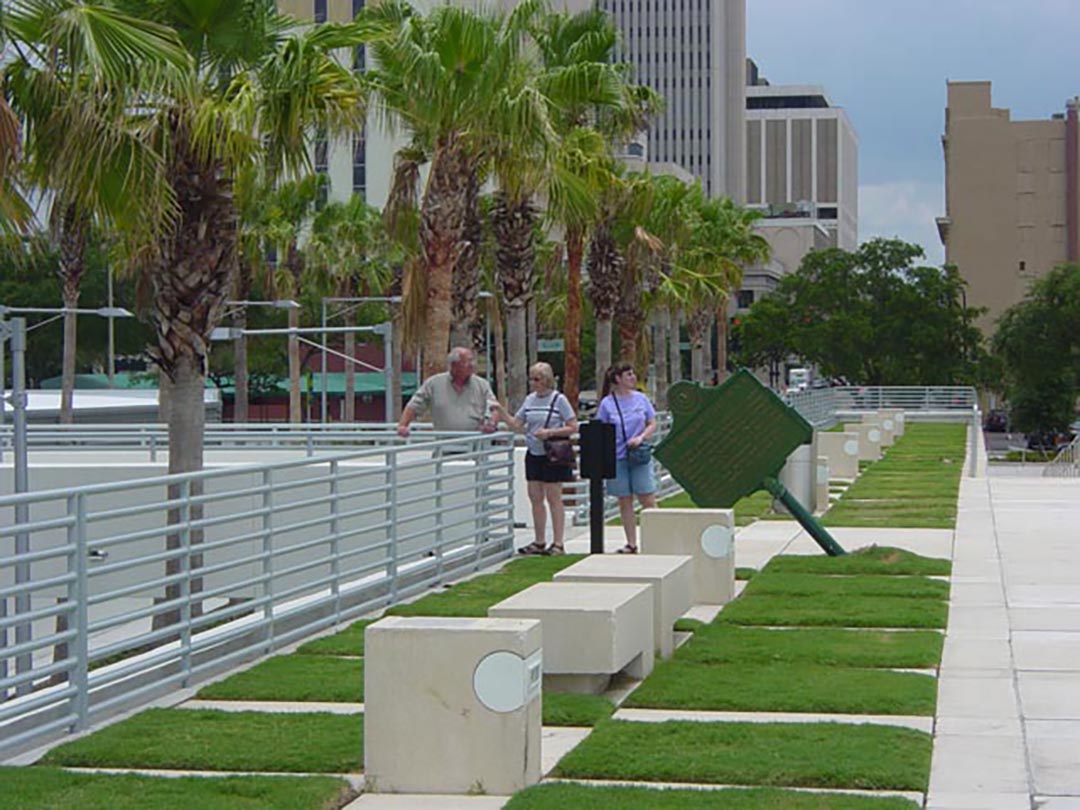 Gary, Surella, and Julie walk through a park with concrete walks around patches of grass and sculptures