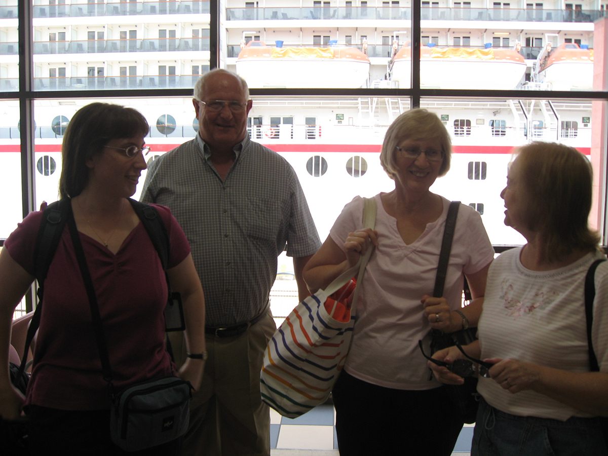 Julie, Gary, Surella, and Gayle stand in front of a window with the cruise ship visible outside