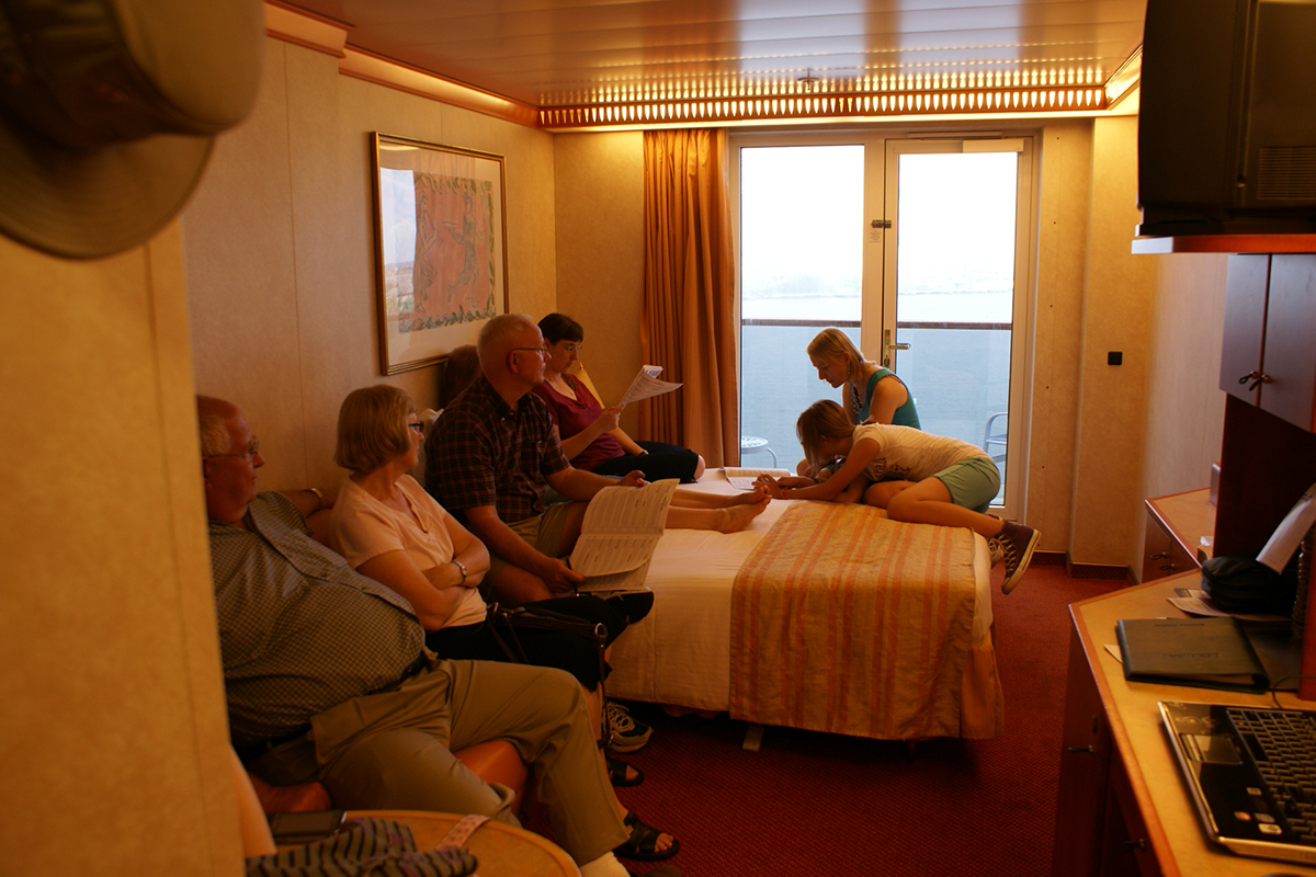 Group of people in a cruise ship stateroom reviewing paperwork