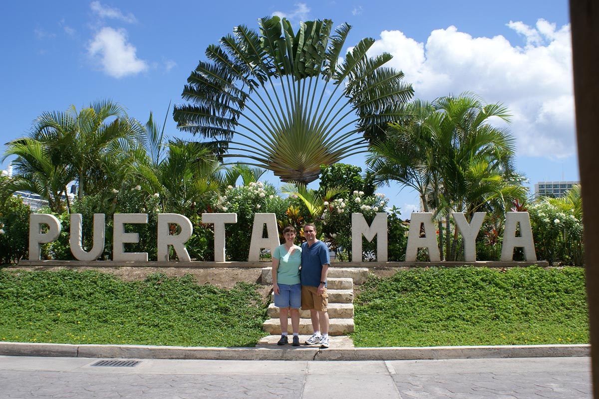 James and Julie pose in front of a Puerta Maya sign