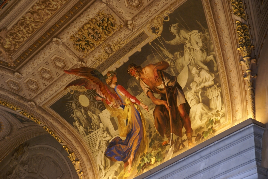 A lifelike painting of two characters in color with highly detailed surrounds gives the illusion that an angel’s wings are sticking out of the painting and covering part of the surround wall