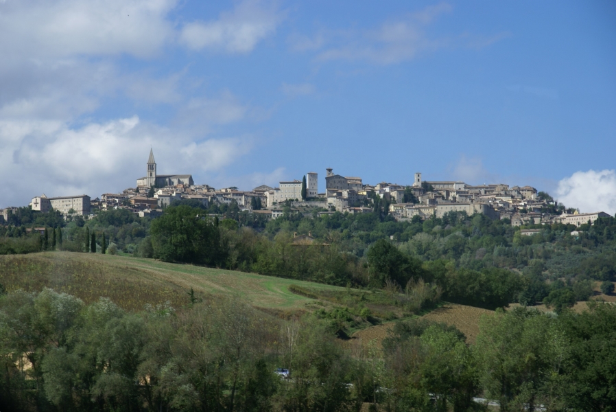 A bell tower extends above the high roof a church on top of a hill as buildings extend along the hilltop and down the slopes
