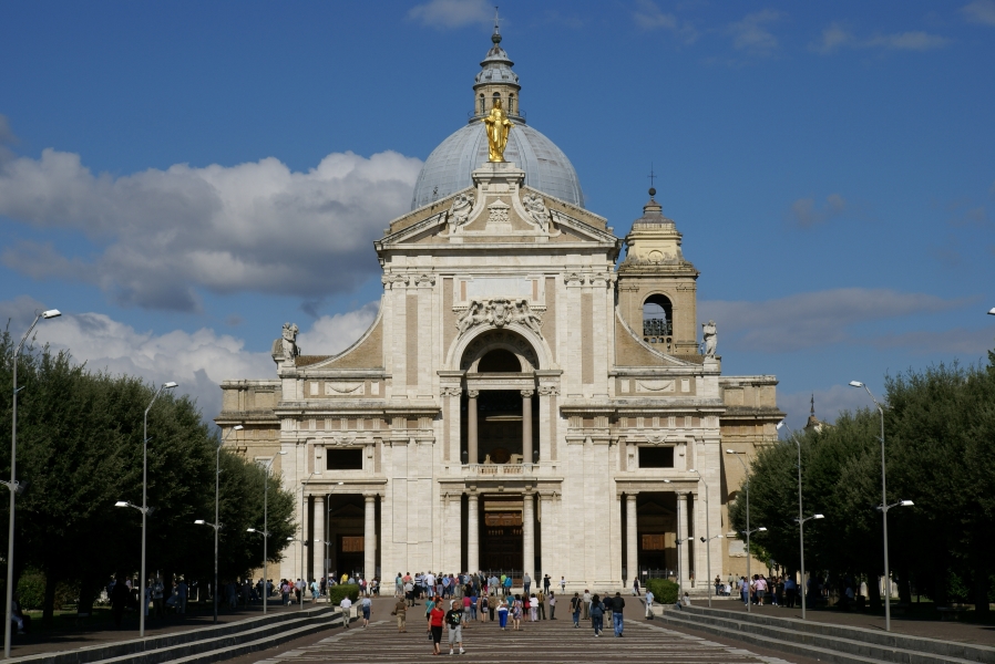 Three steps run on each side of a wide plaza space leading to the entrance of a church with a bright white façade topped by a gold angel with a gray slate dome rising from the building beyond