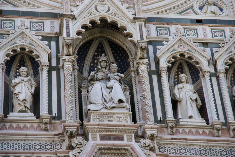 Bright white statues of the apostles and the Mother Mary holding the Christ Child are set in niches with painted backgrounds and surround by intricate tile mosaics