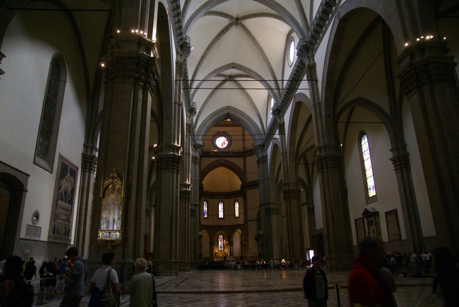 Dark gray stone columns and trim support the high arched ceilings of plain white plaster inside the Florence Cathedral; only a few markers on the walls record famous patrons