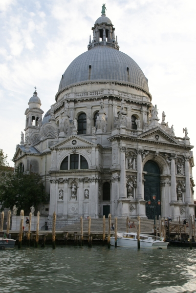 A large round dome with green state tops a light gray stone church building with a hexagonal base featuring statues and eight distinct chapel or entry extensions