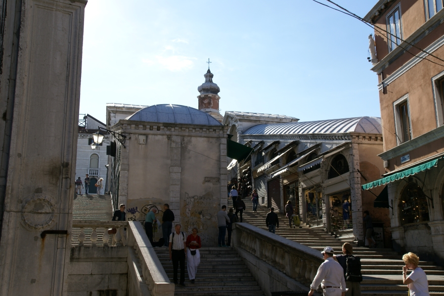 Stone steps run up between two narrow buildings with shops at different levels