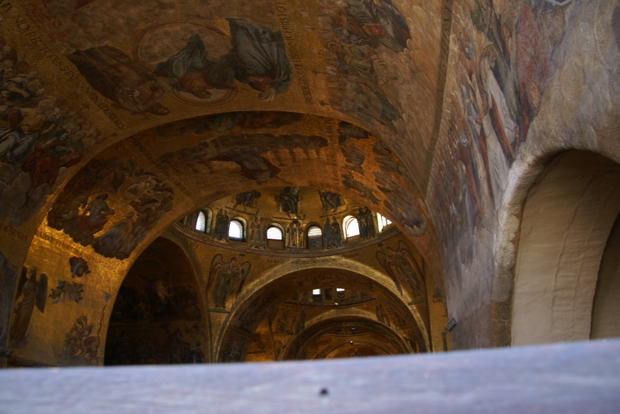 Large figures made of mosaic tiles surrounded by gold tiles fill arched ceilings