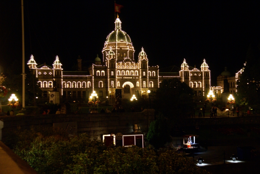 A building with a wide front, arcades along the second floor connect short two-towered blocks to a central taller block with tower small towers on either side of a higher domed structure has stings lights along the edges of the walls and roof lines