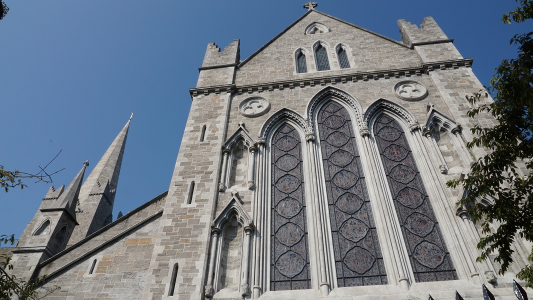 Clear blue skies above a white stone church with steeply sloped roof and tall narrow stained-glass windows
