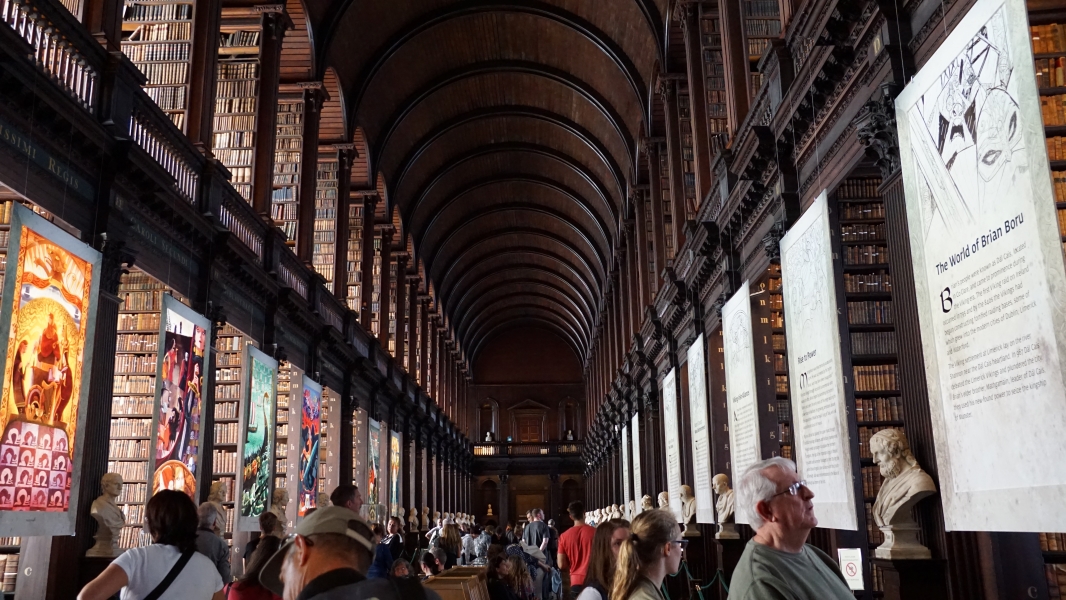 Dark wood arches span a walkway passing between rows of wooden bookshelves