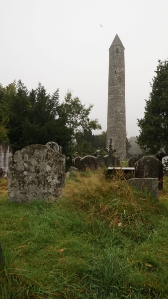 A round stone tower with a conical top sticks up above the trees
