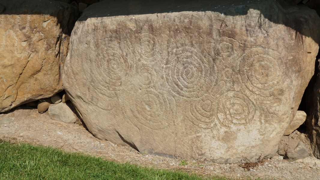 Megalithic art carved into a large stone at Knowth, Ireland, featuring intricate spiral patterns and other geometric designs