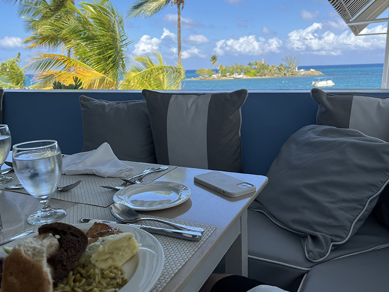A plate of food on a table against the railing with Sapphire Island in the distance