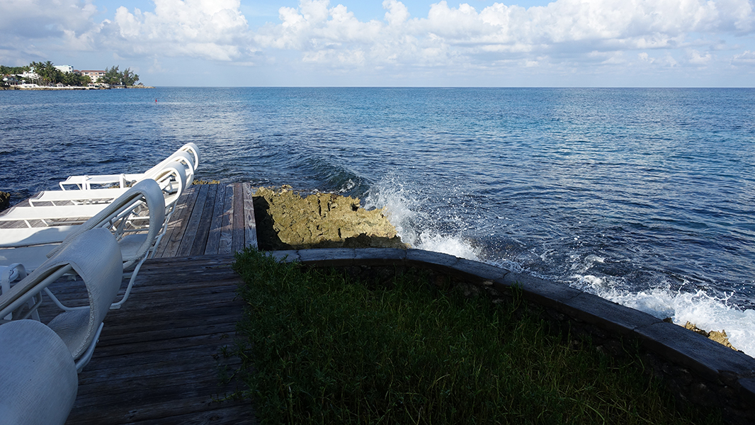 Water sprays up from a wave hitting the jagged coast of the island