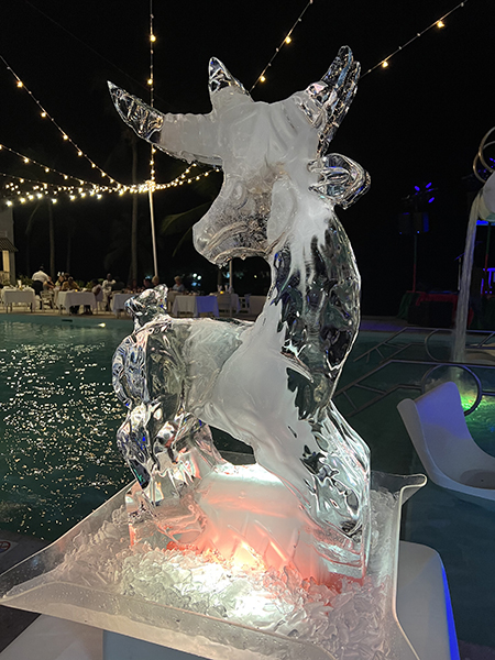 A reindeer ice sculpture on a table near a swimming pool