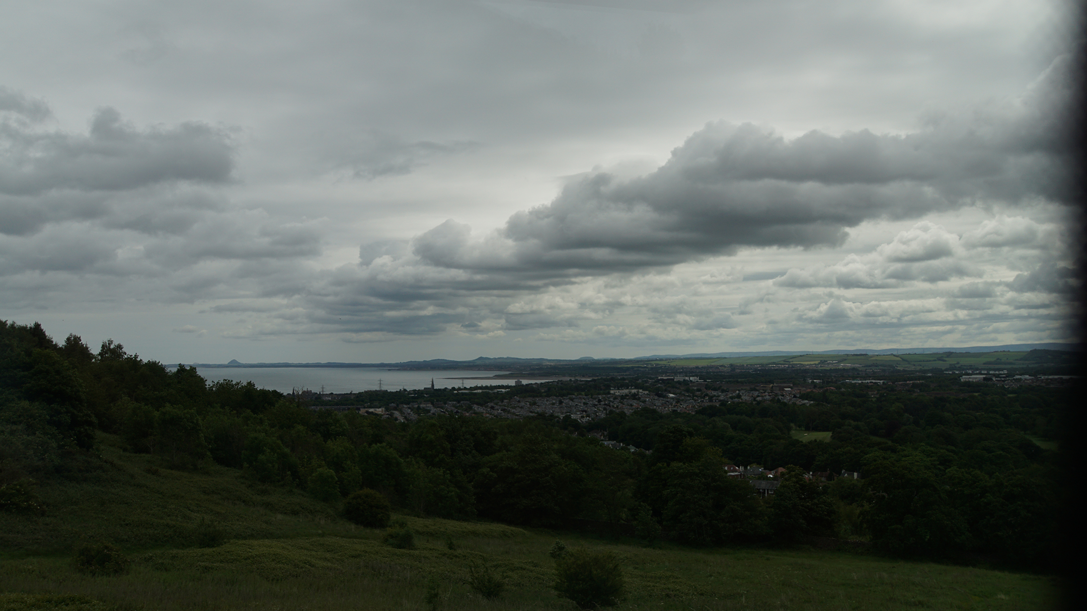 Coastline and buildings from elevated green hill