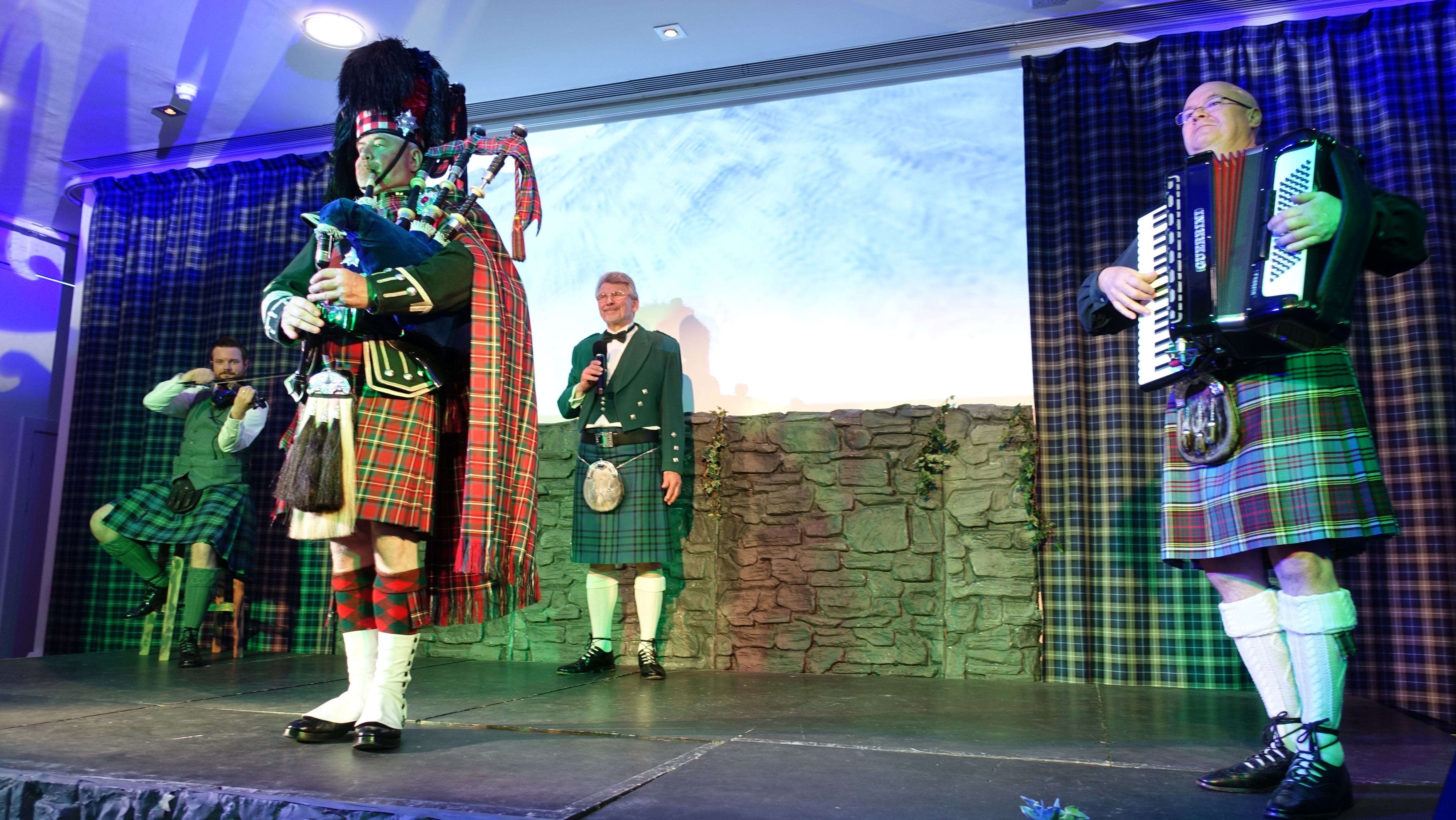 Three musicians playing the fiddle, accordian, and bagpipes