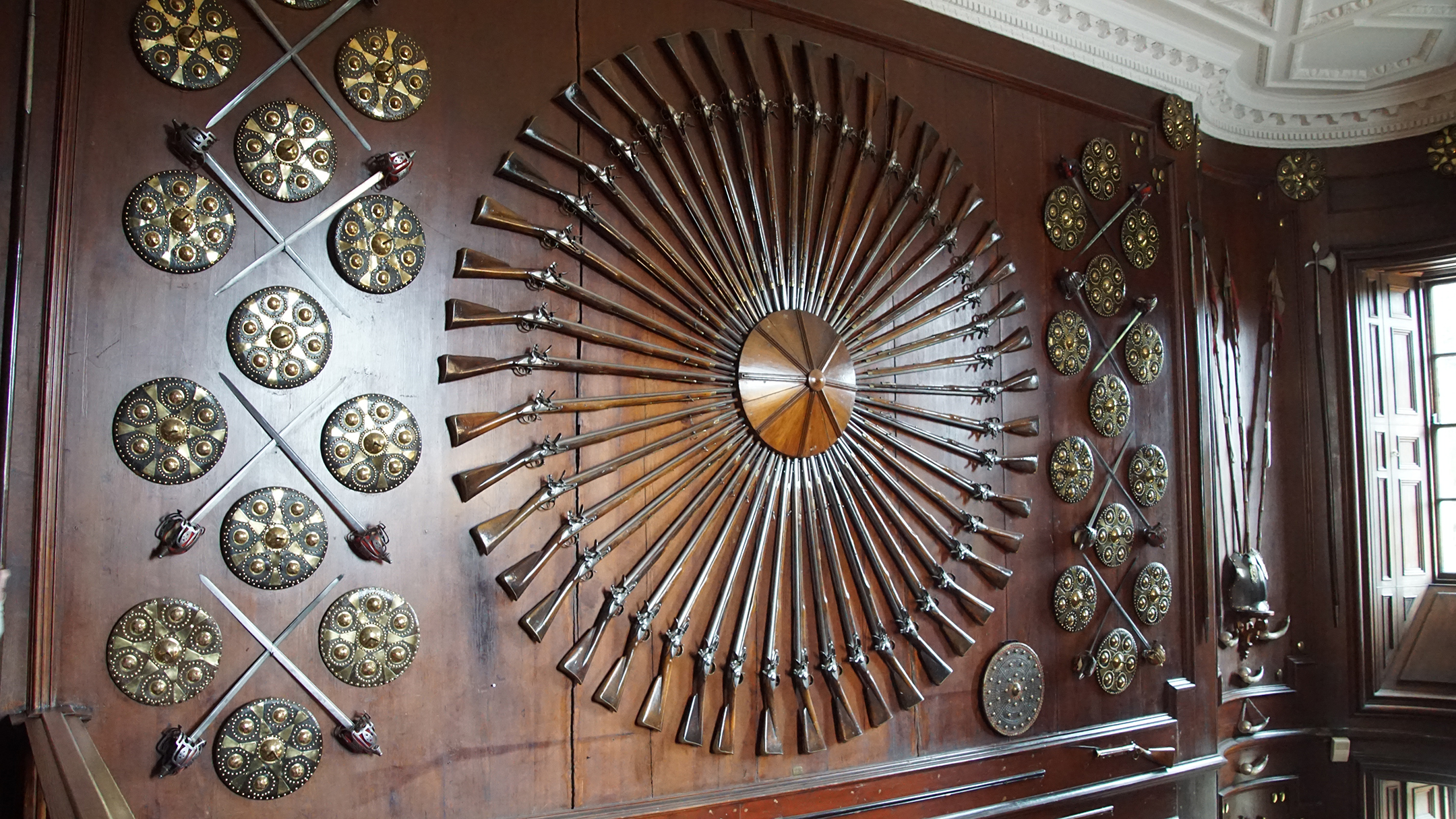 Swords and rifles arrayed on wood paneled walls