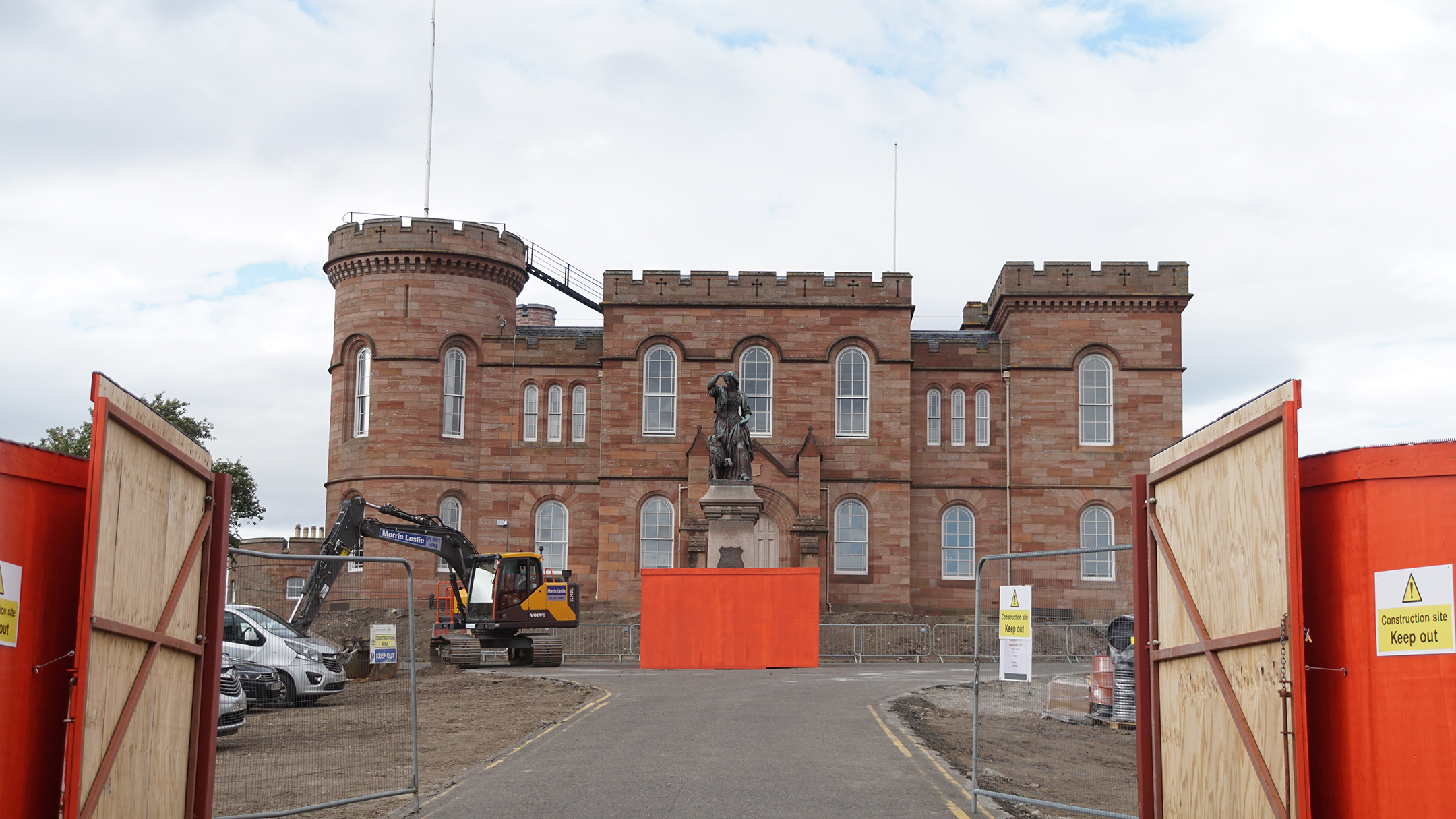 Red stone castle behind orange construction barrier walls