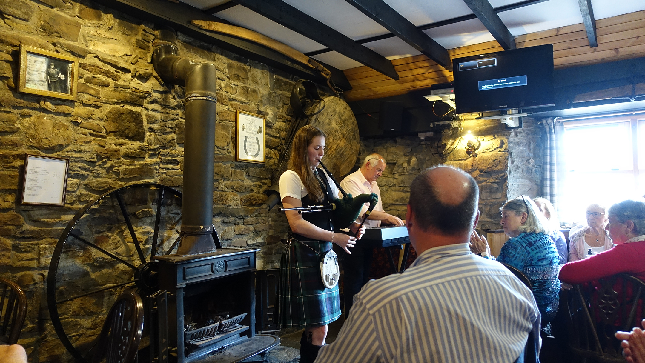 Young woman playing bagpipes in a crowded pub