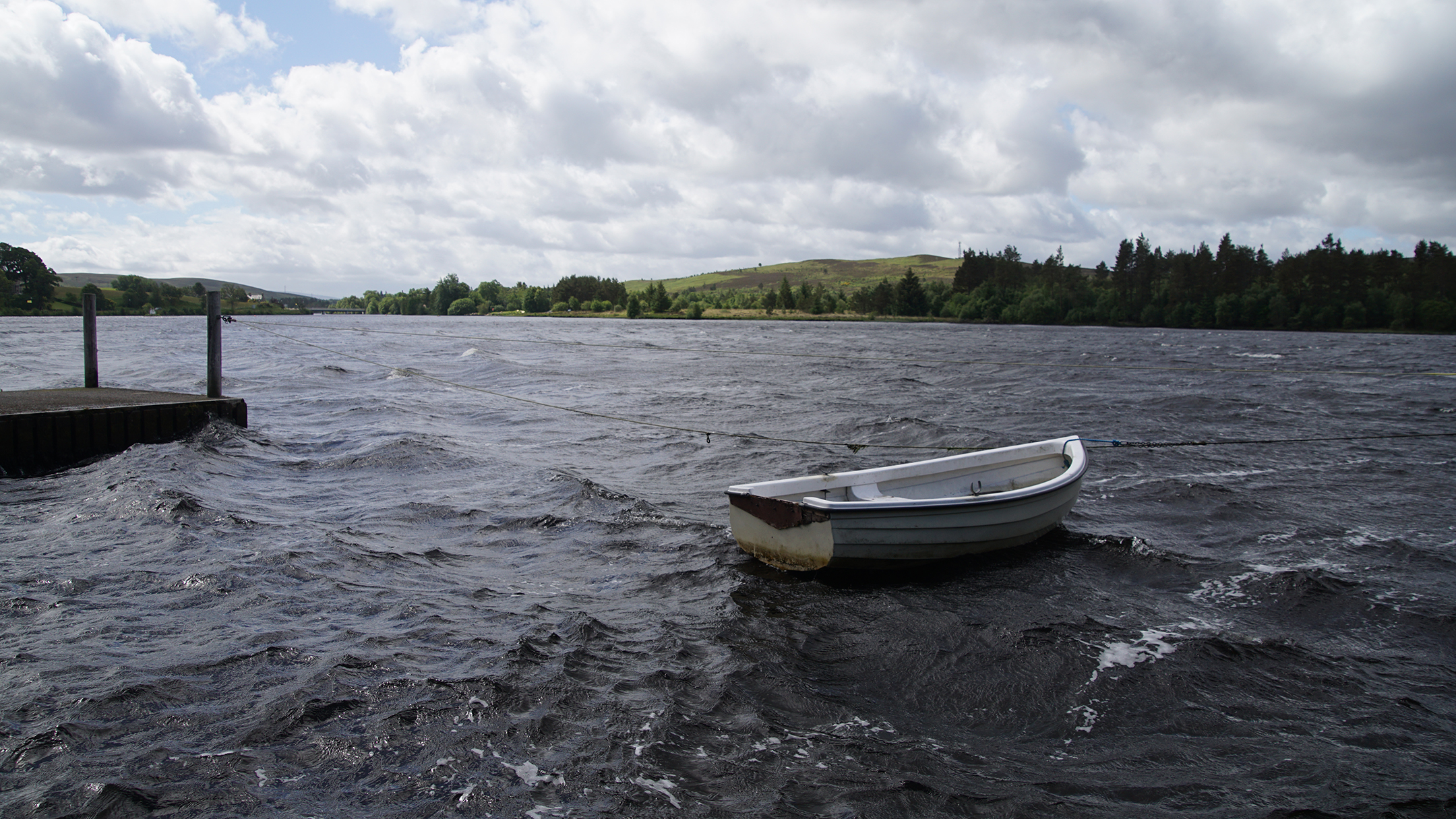 A boat bobs in the waves on a windswept lake