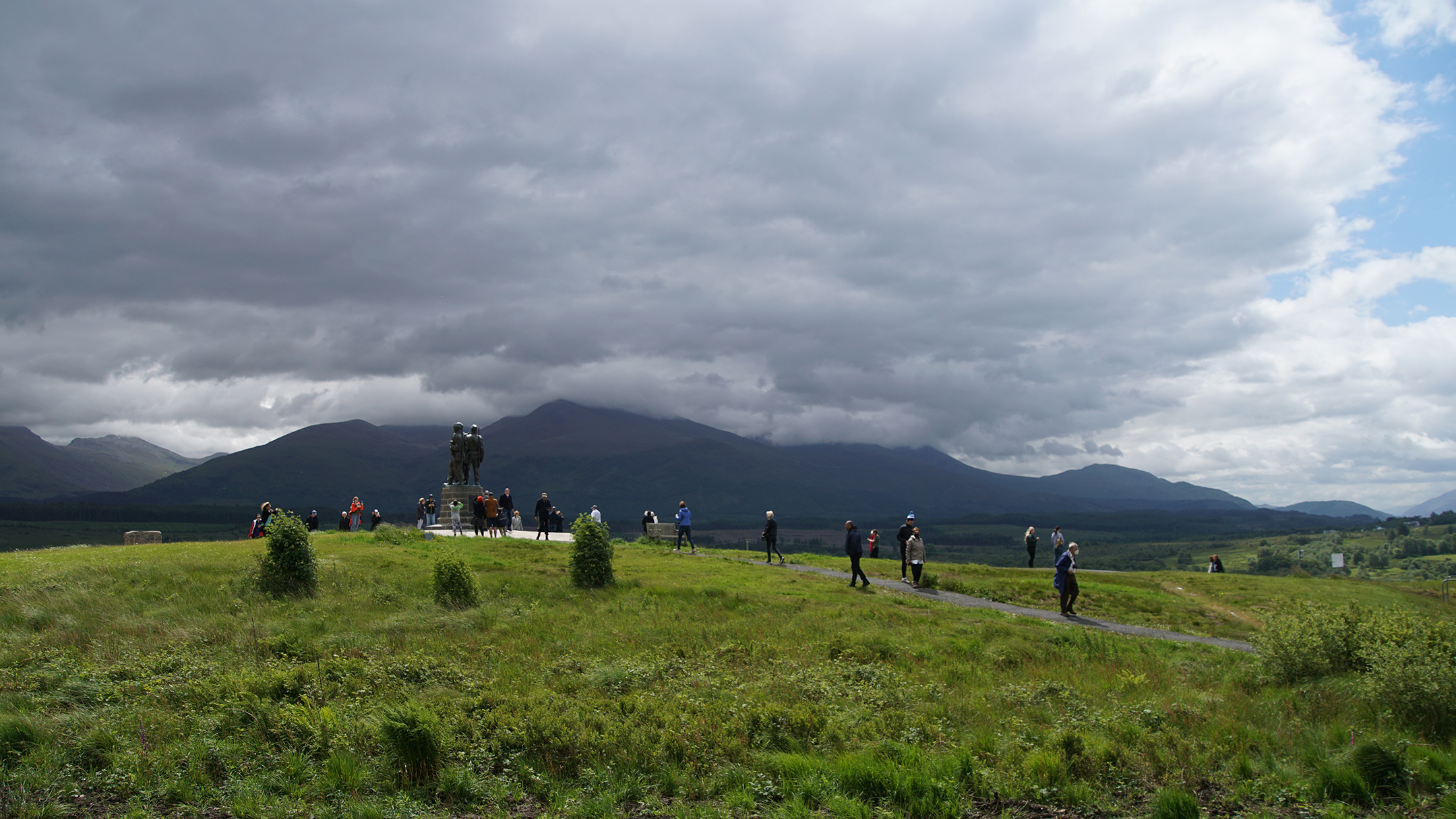 A statue sits on a low hill near a range of larger mountains