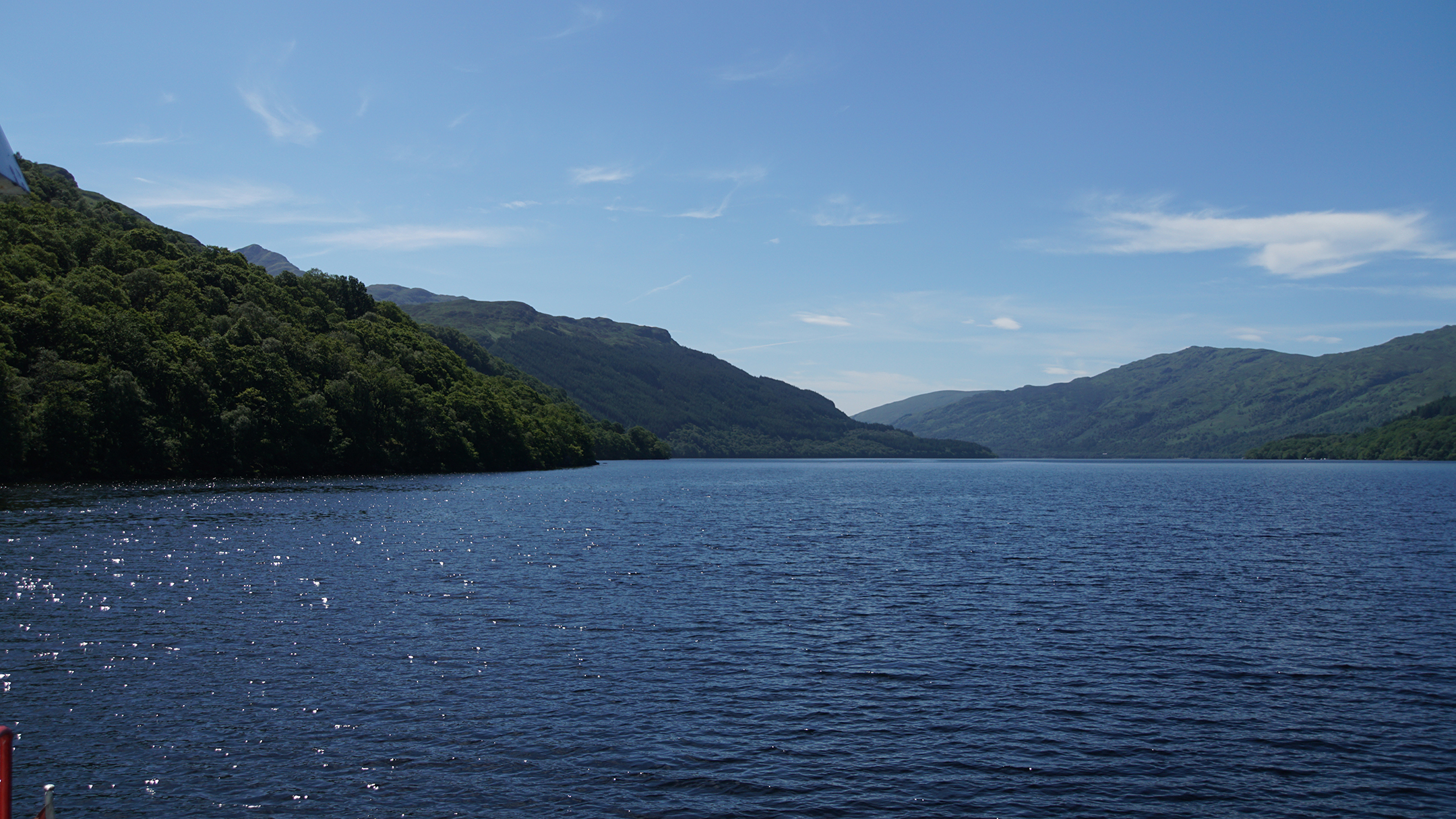 Green tree covered hills running down to a deep blue lake
