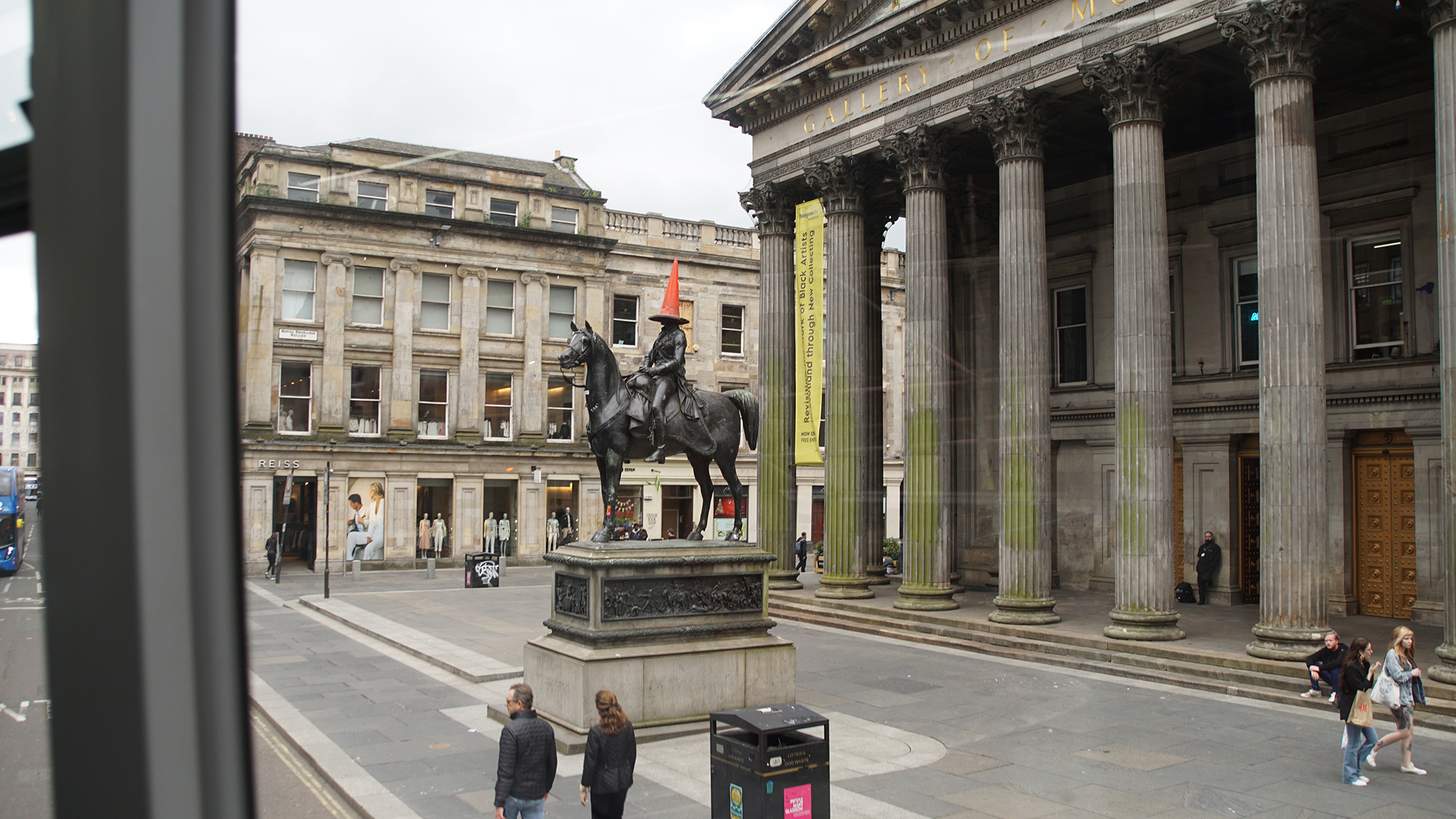 Statue of man on horse with orange traffic cone for a hat