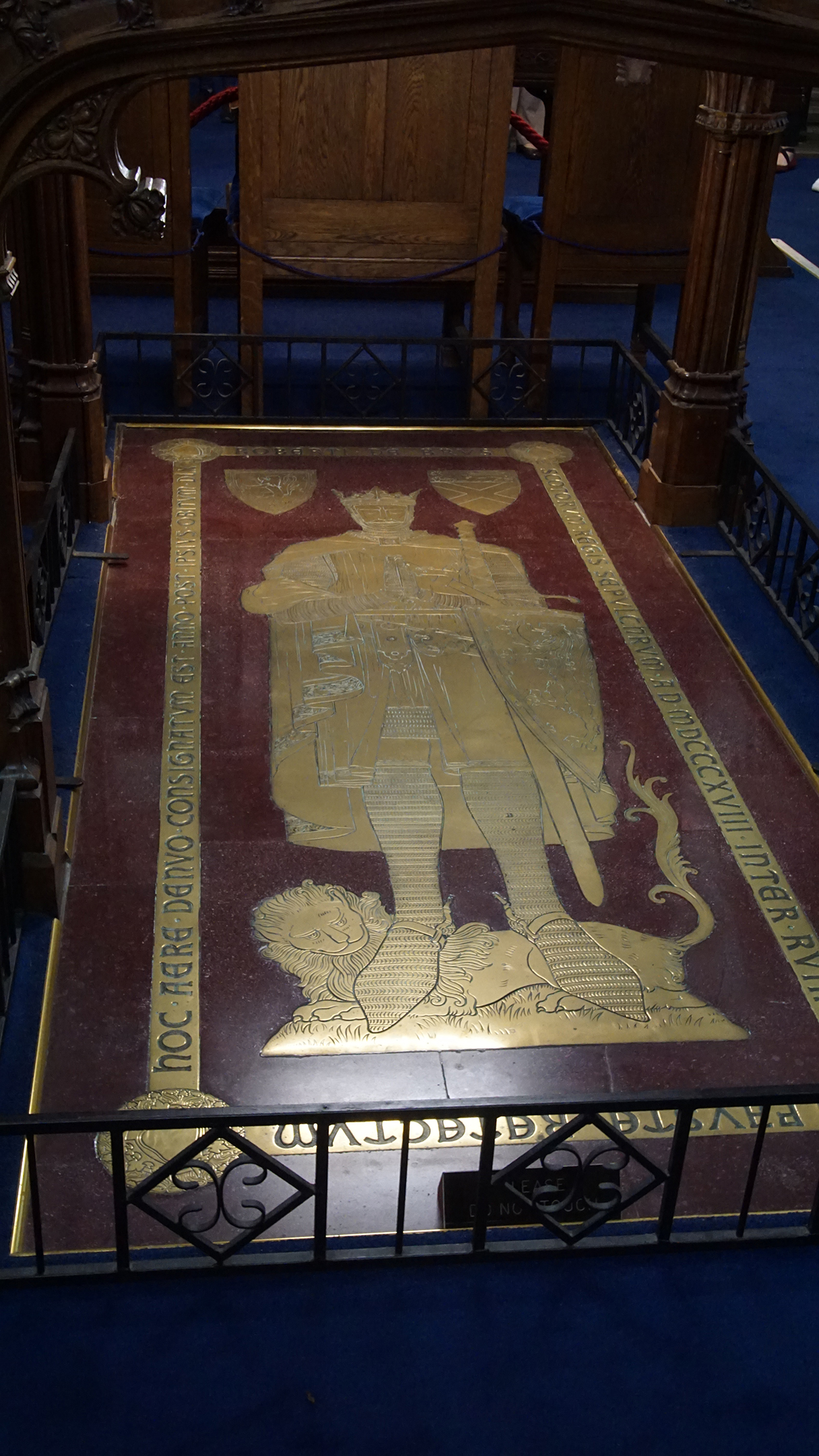 A red marble slab with gold inlay of a knight and latin text