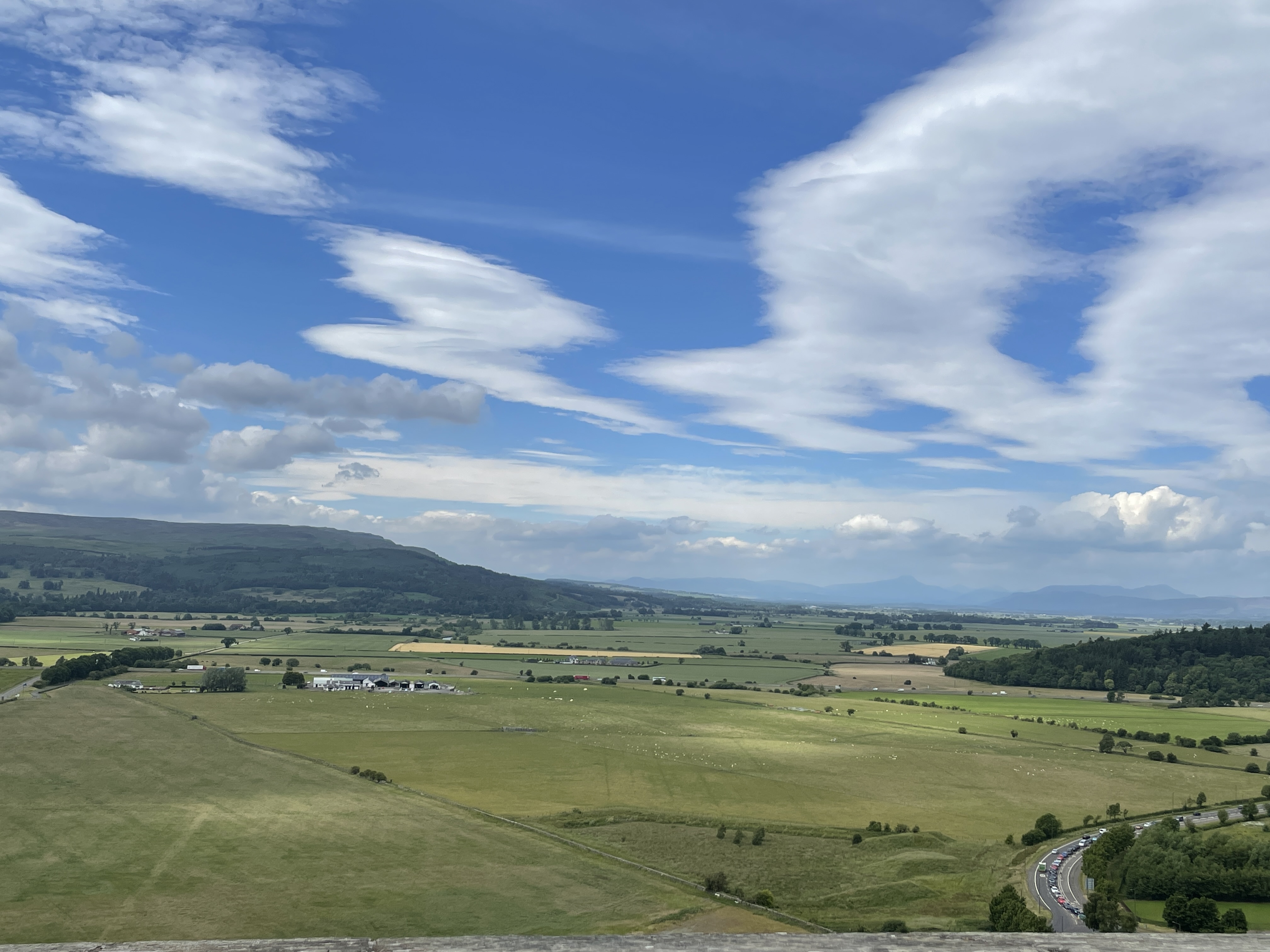 Green fields extending into the distance with tree covered hills