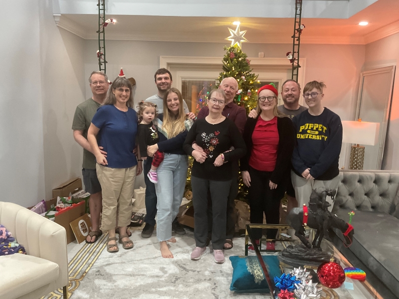 10 members of a family pose for a photo in front of a Christmas tree