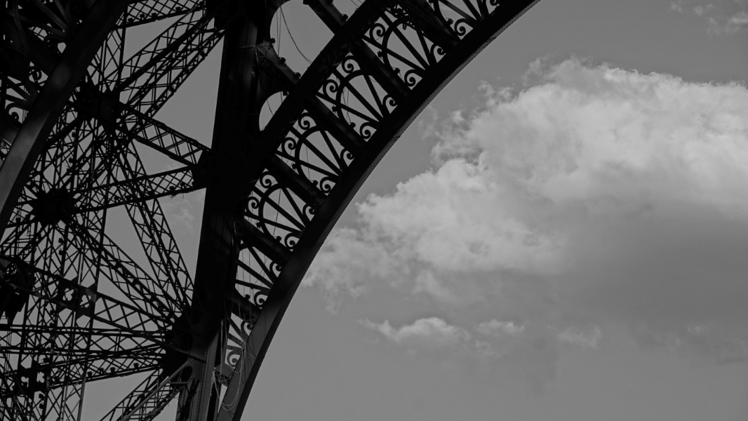 A black-and-white detail of the ornamental iron work in the arch of the Eiffel Tower